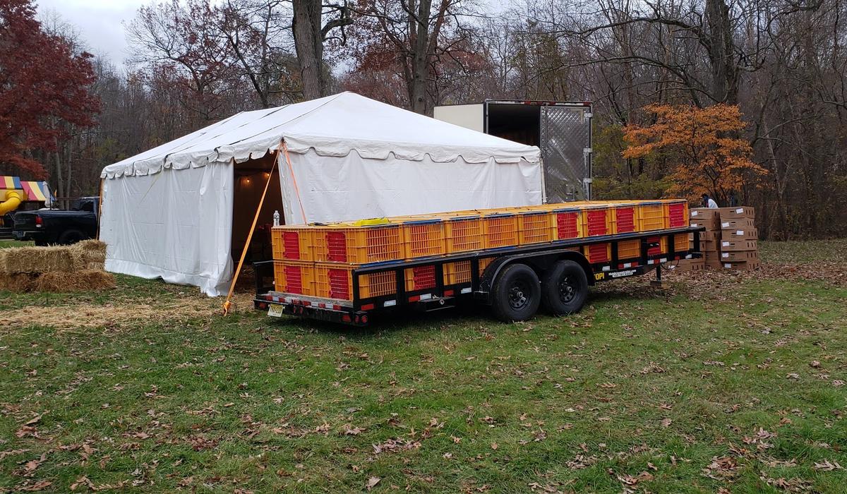 A trailer loaded with poultry crates parked beside the pick up tent at the farm