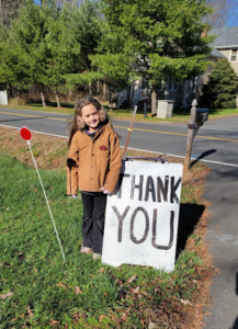 Young girl standing next to Thank You sign outside Spring Valley Turkey Farm in New Jersey during fall season