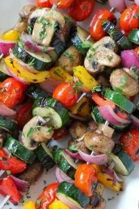 Grilled vegetable skewers with zucchini, peppers, onions, and mushrooms at an outdoor spring cookout.
